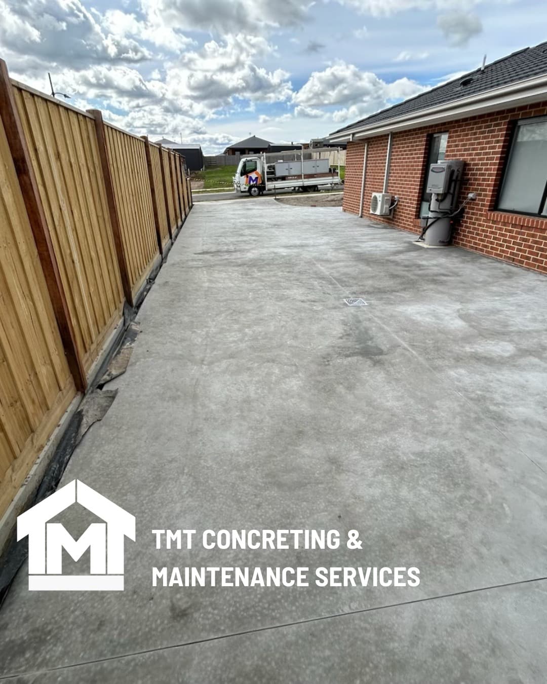 Finished concrete driveway between fence and rendered brick home, Gippsland