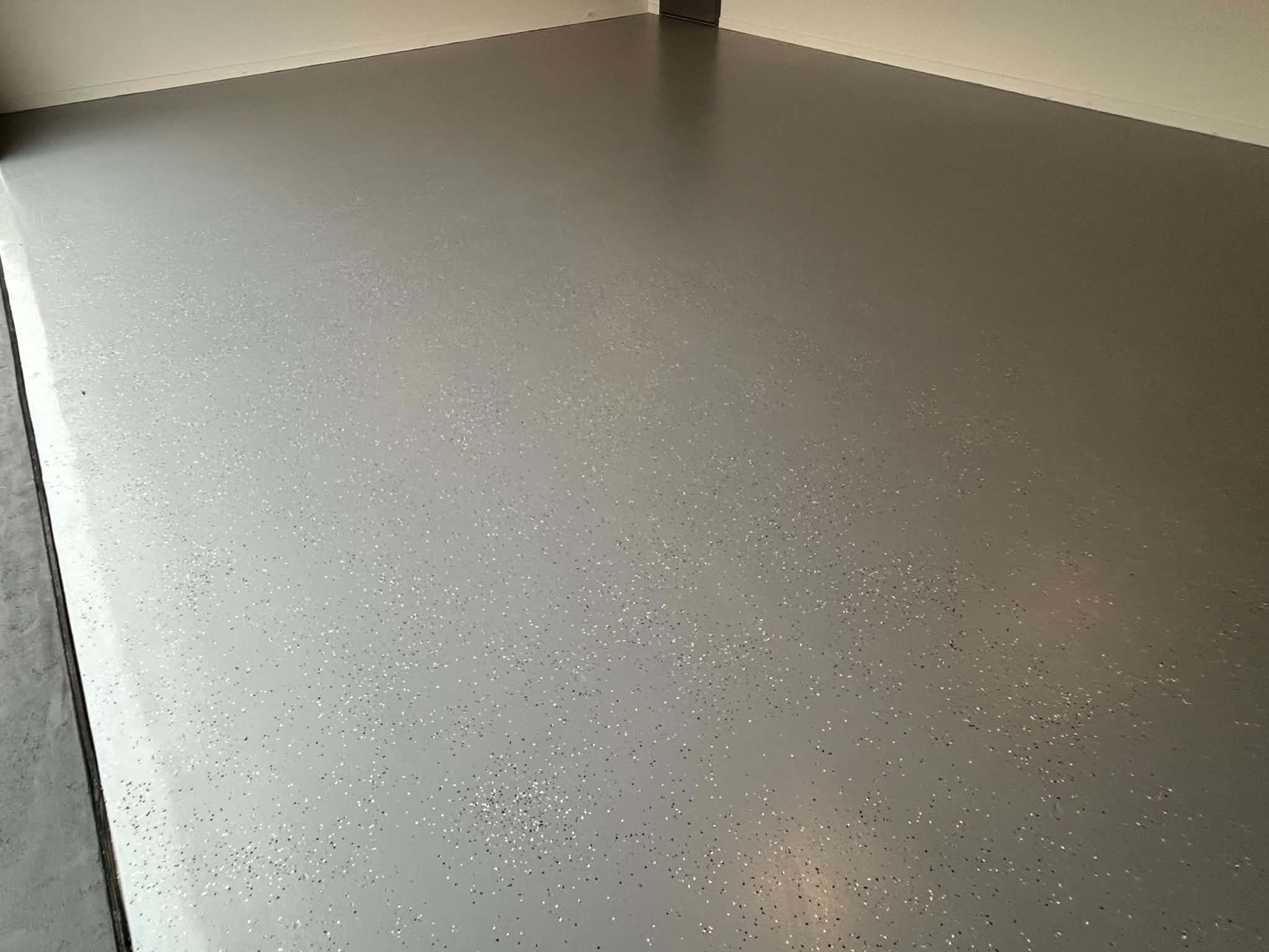 Light-grey flake epoxy garage floor meeting painted wall in corner, Sale